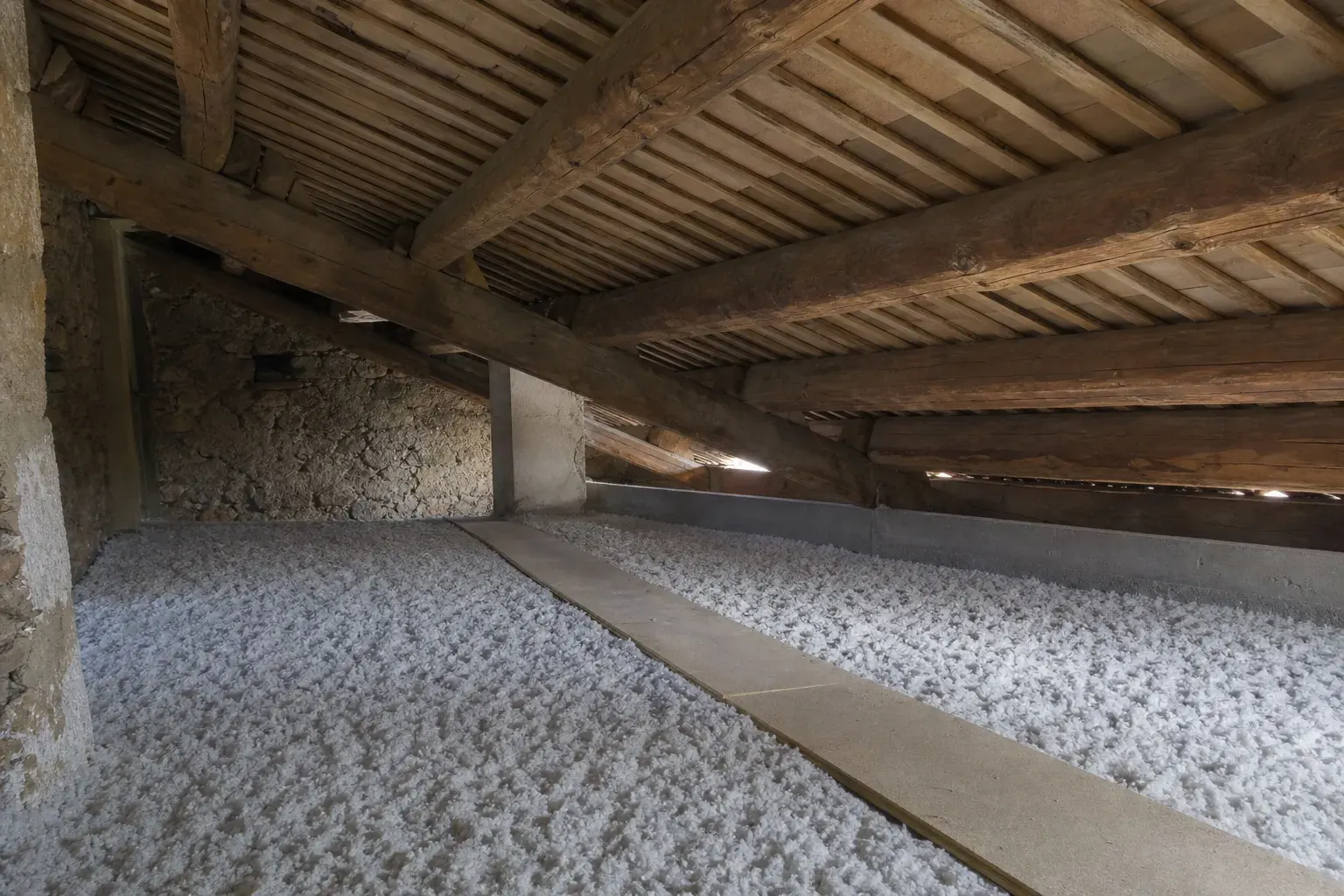 Plancher de comble recouvert d’isolant soufflé et arasé, avec une passerelle de service posée en travers