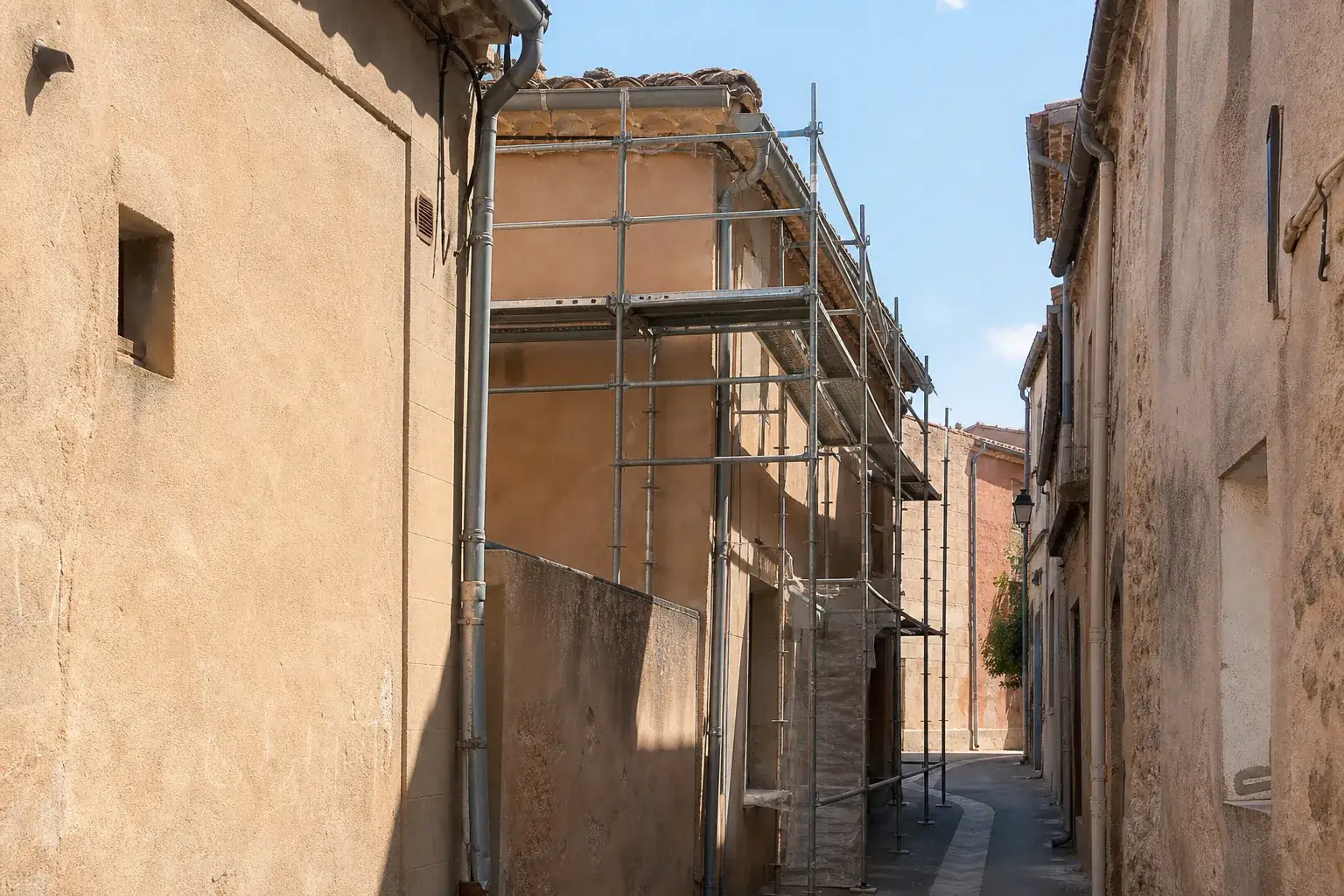 Échafaudage monté dans une ruelle de centre ancien à peine plus large qu’une voiture